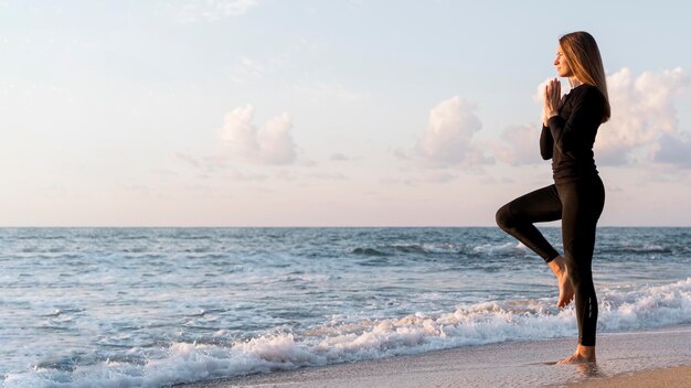 Woman meditating on the beach with copy space