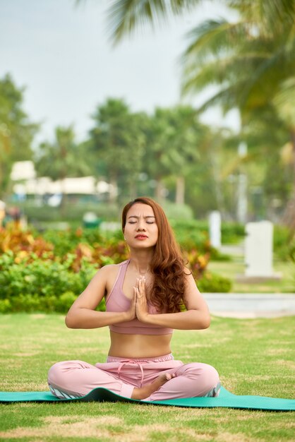 Woman meditating on green meadow