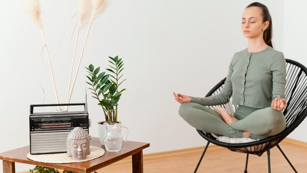 Woman meditating at home on chair