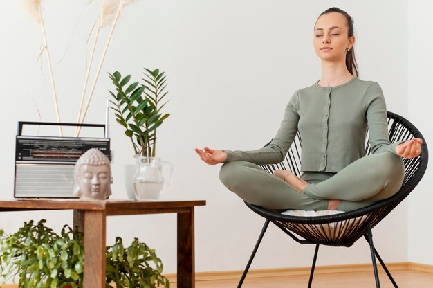 Woman meditating at home on chair