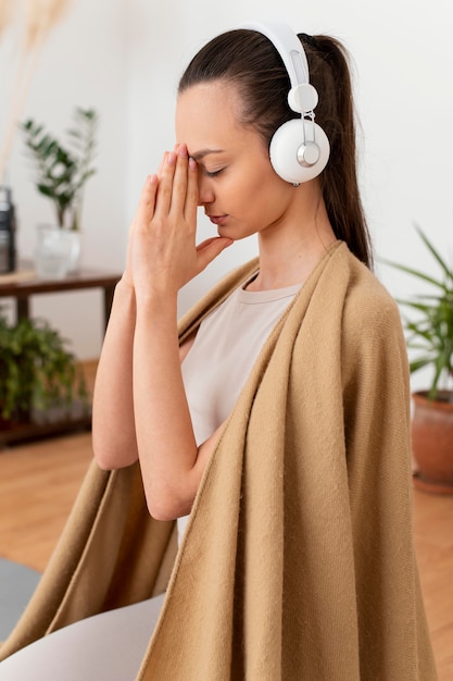 Woman meditating at home with headphones
