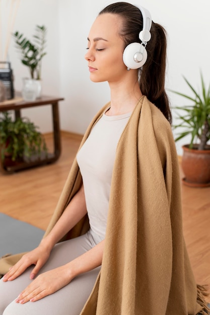 Woman meditating at home with headphones