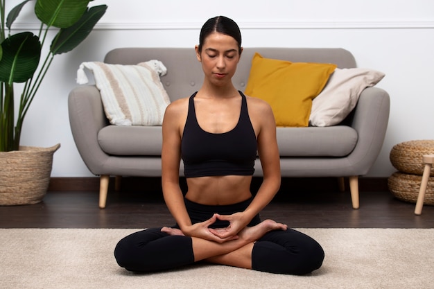Woman meditating indoors  full shot