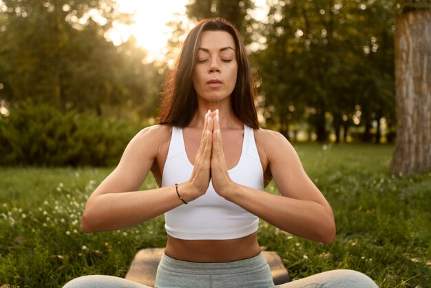 Женщина медитирует на открытом воздухе, вид спереди