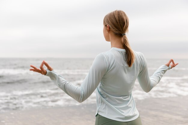 Woman meditating at seaside medium shot