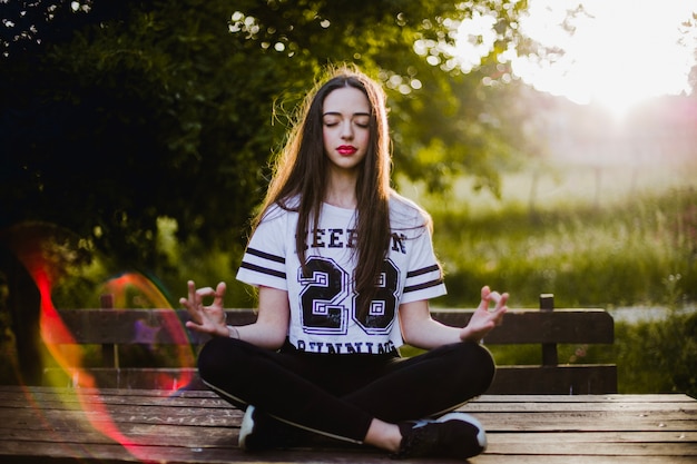 Foto gratuita donna meditando sul tavolo nel parco