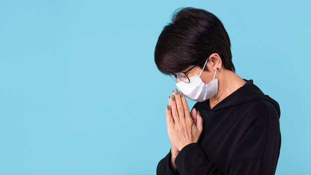 Free photo woman meditating while wearing a face mask with copy space