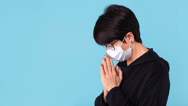 Woman meditating while wearing a face mask with copy space