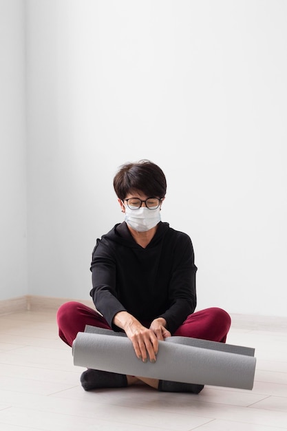 Free photo woman meditating while wearing a face mask