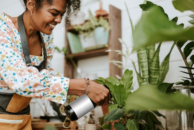 植物店で水スプレーで植物を霧化する女性