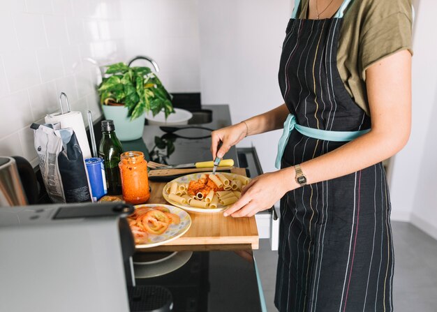 Женщина смешивания соуса в макароны на кухне счетчик