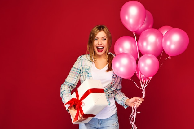 Woman model celebrating and holding box with gift present and pink air balloons