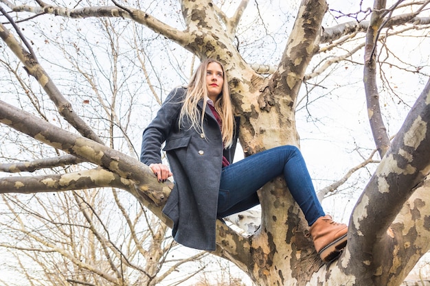 Woman model sitting on tree branch