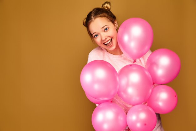 Woman model with pink air balloons on golden wall