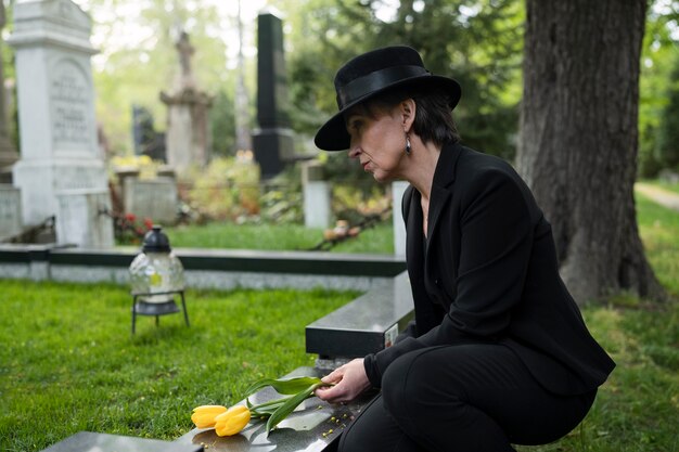 Woman mourning in the cemetery next to grave