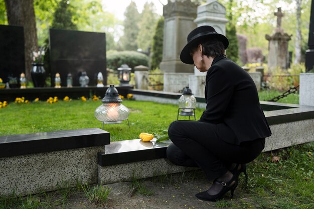Woman mourning in the cemetery next to grave