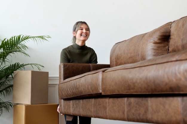 Женщина перемещает диван в новом доме