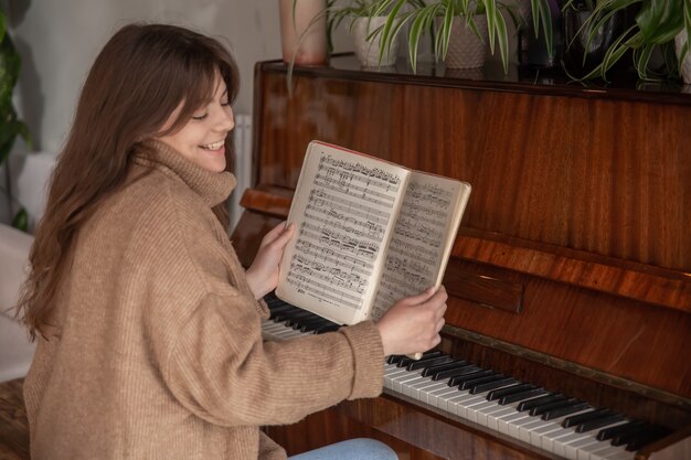 A woman musician teaches a piece while sitting in front of the notes on the piano.