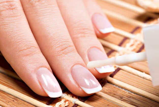 Woman in a nail salon receiving manicure by a beautician. Beauty treatment concept.