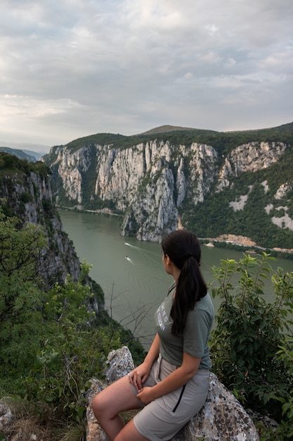 Foto gratuita donna in un paesaggio naturale che guarda a un fiume