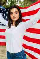 Foto gratuita donna in natura che tiene bandiera americana