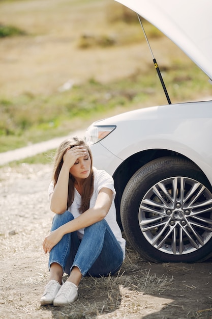 壊れた車の近くの女性が助けを求める