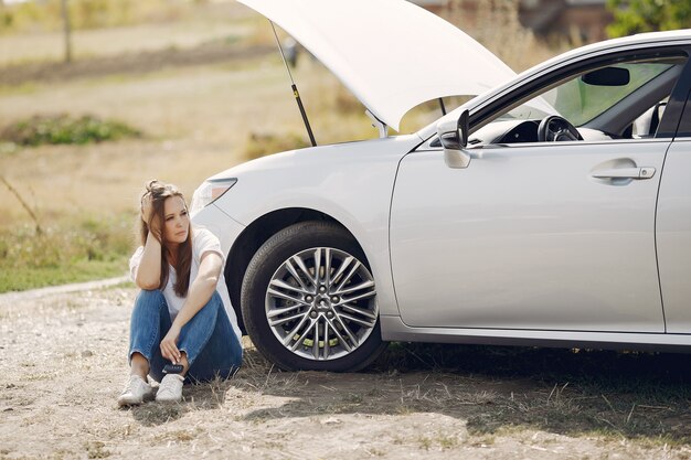 壊れた車の近くの女性が助けを求める