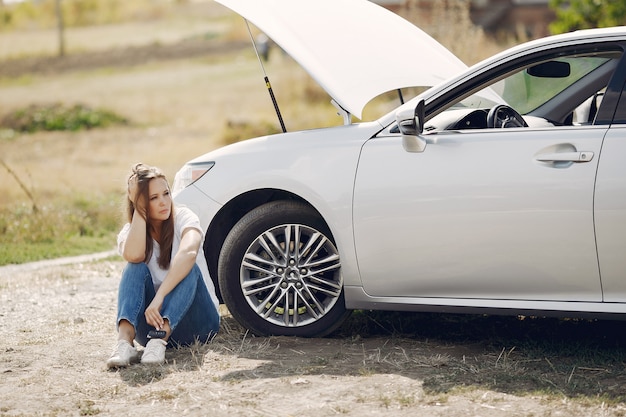 壊れた車の近くの女性が助けを求める