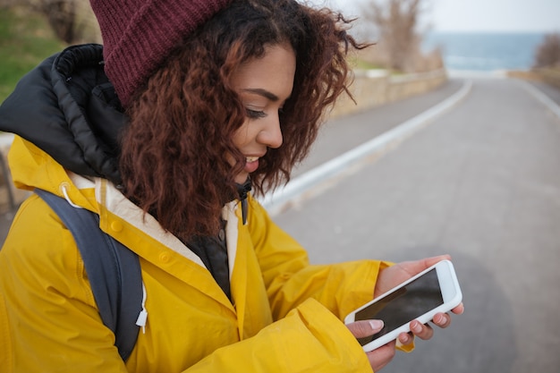 Foto gratuita donna vicino alla strada facendo uso dello smartphone