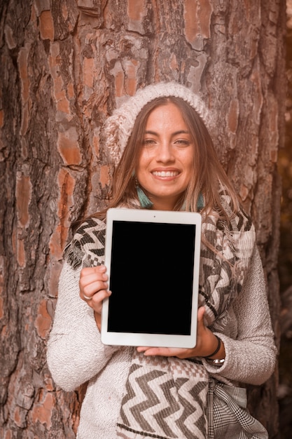 Free photo woman near tree showing tablet