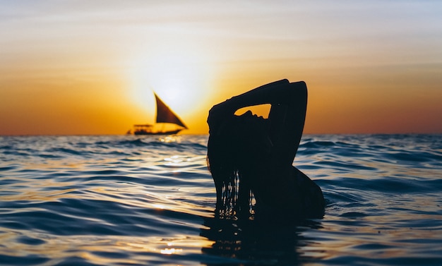 Woman in the ocean in the sunset time