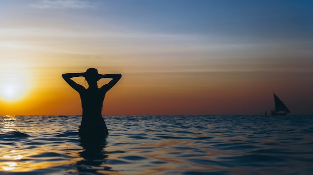 Foto gratuita donna nell'oceano nell'ora del tramonto