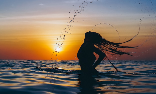 Woman in the ocean in the sunset time