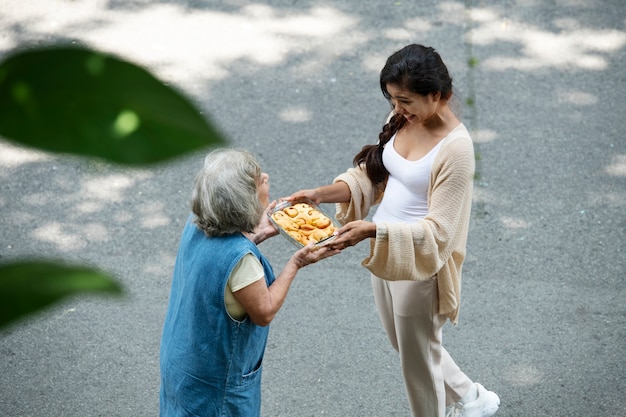 Free Photo woman offering food to neighbor
