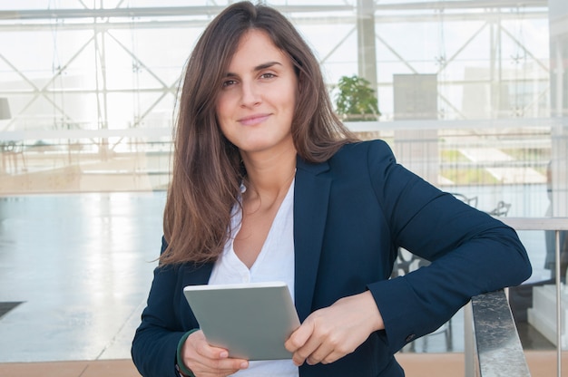 カメラを見て、手でタブレットを保持しているオフィスの女性