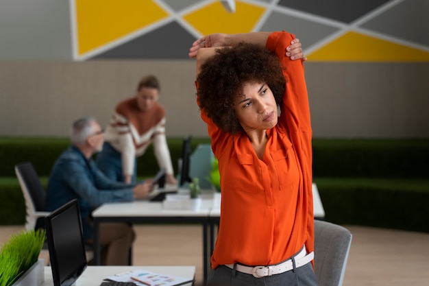 Foto gratuita donna in ufficio che si estende durante una giornata lavorativa