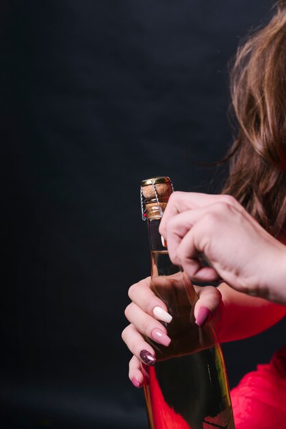 Woman opening champagne bottle 