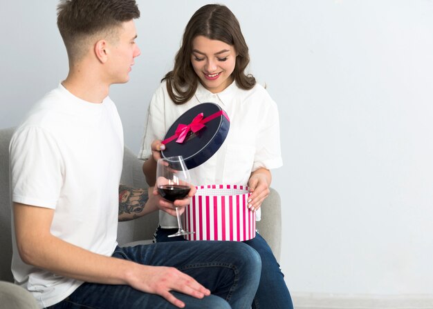 Woman opening gift box on couch 