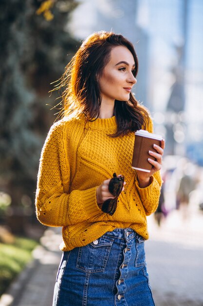 コーヒーを飲みながらオレンジ色のセーターの女性