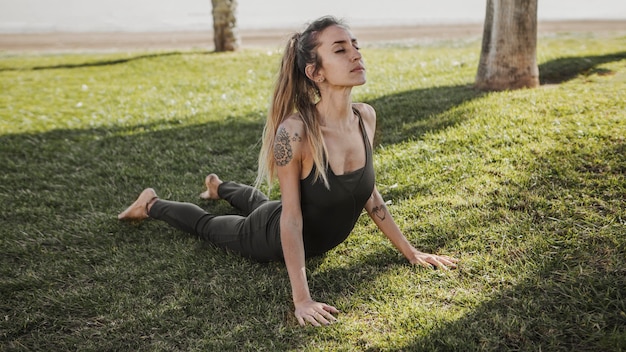 Free photo woman outdoors on the grass doing yoga