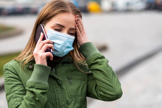 Woman outdoors wearing a mask and talking on the mobile phone