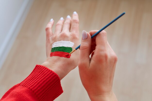 Женщина рисует болгарский флаг на руке