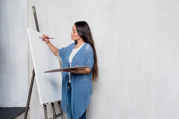 Женщина рисует на холсте