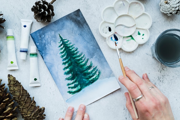 Woman painting the christmas tree with paint brush