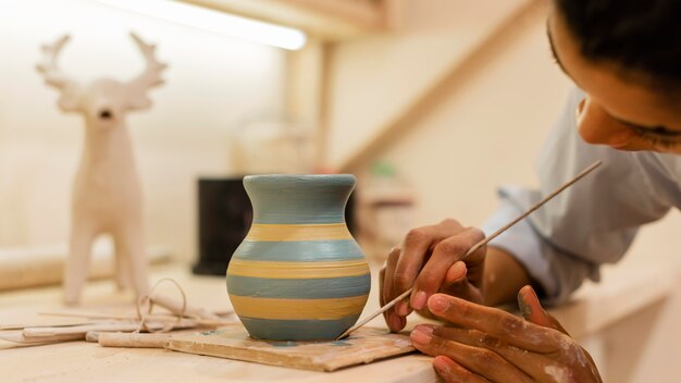 Woman painting clay pot close up