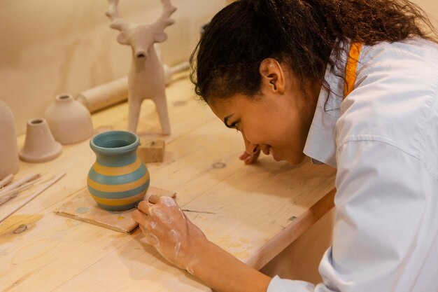 Woman painting clay pot close up