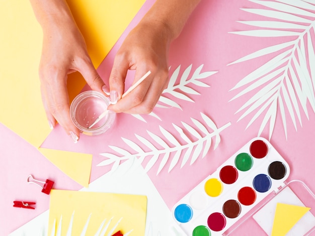 Woman painting cup with watercolor paint