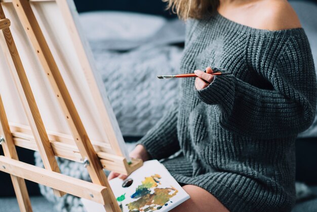 Woman painting in front of bed