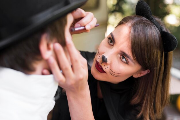 Woman painting man's face close-up