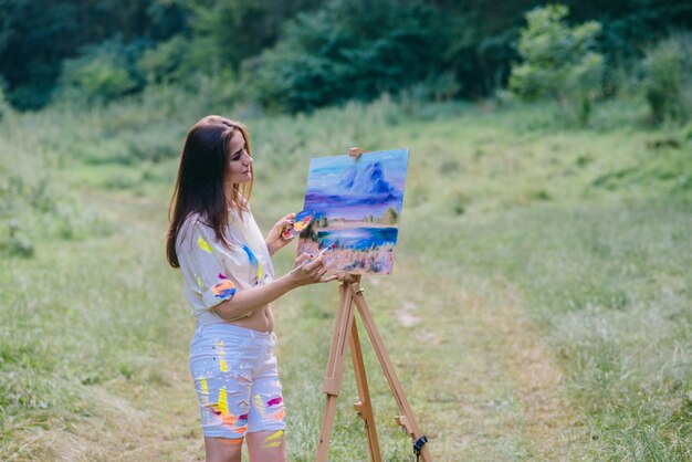 Woman painting a picture in the middle of nature